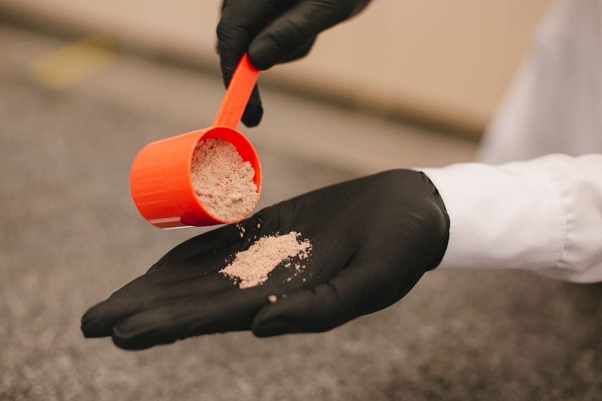 White granular chemical being measured with a scoop