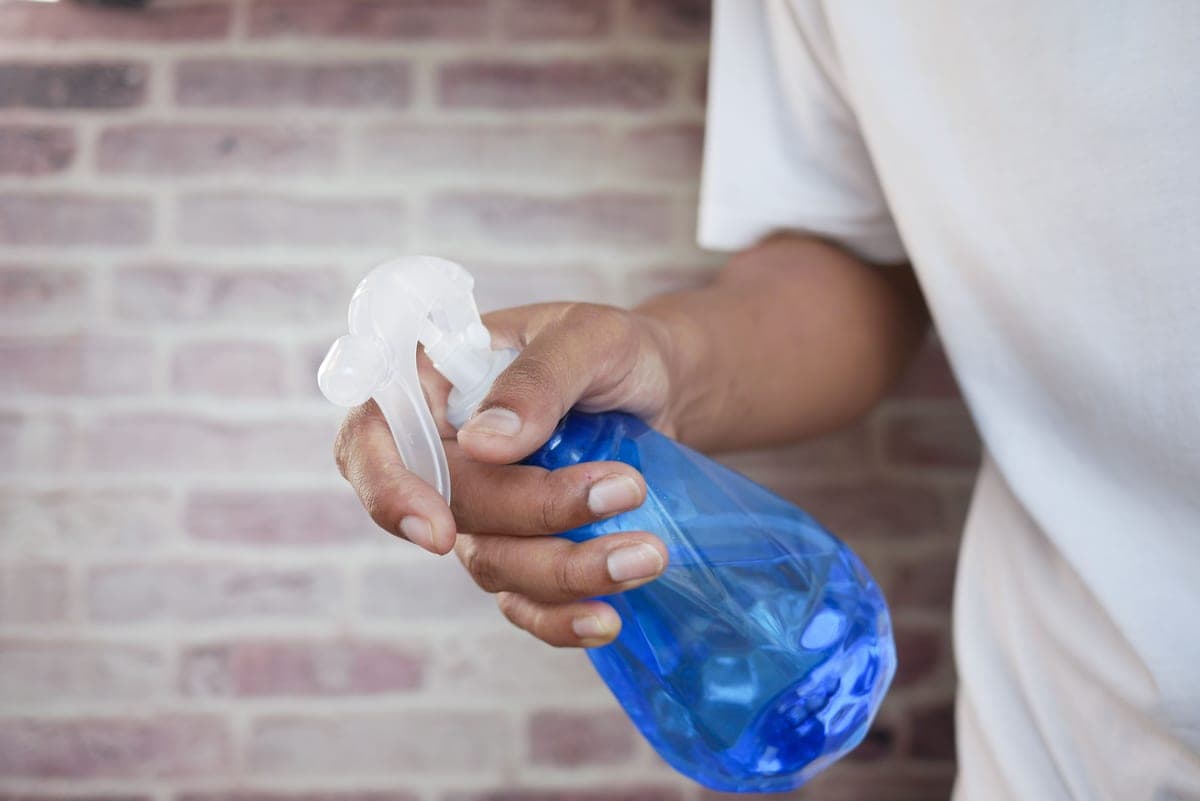 A spray bottle of cleaning solution beside a cloth