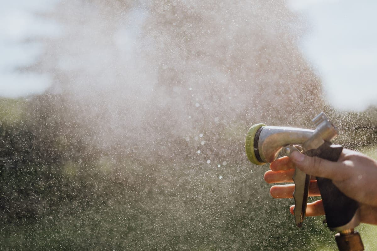 A garden hose nozzle spraying a fan of water
